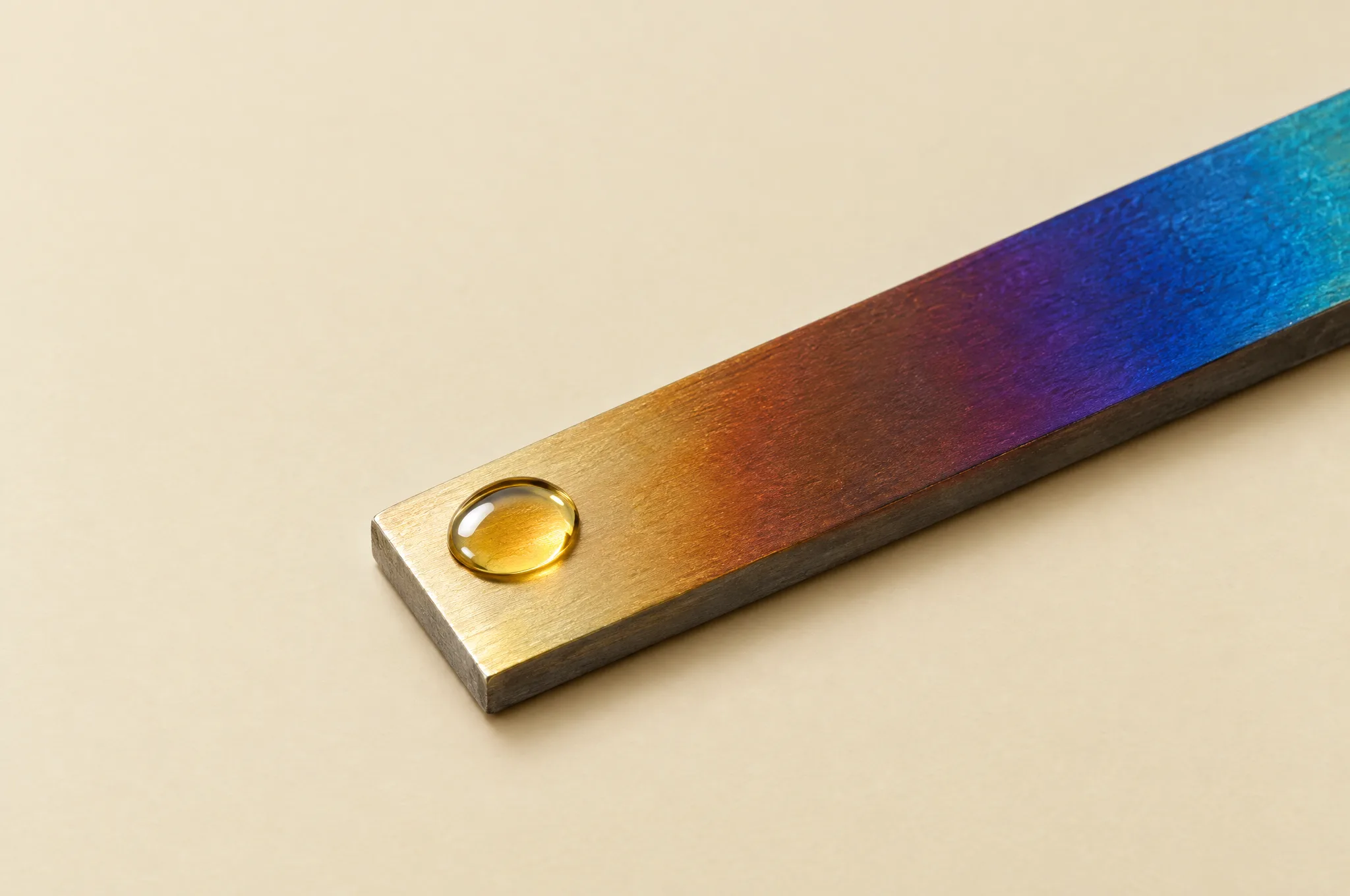 A drop of golden oil on a bar of heat-tinted steel.